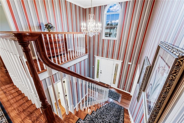 stairs with hardwood / wood-style flooring and a chandelier