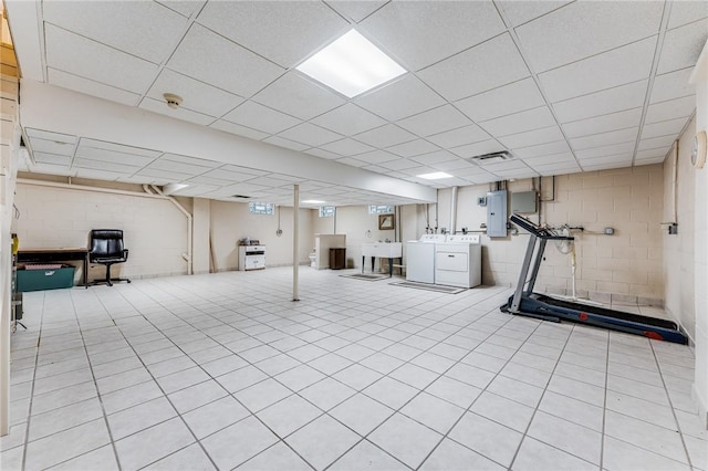 workout area featuring a paneled ceiling, electric panel, sink, and washer and dryer