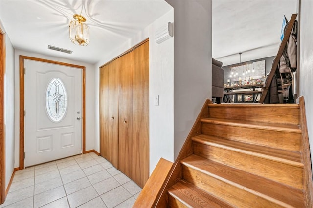 tiled entryway with a notable chandelier