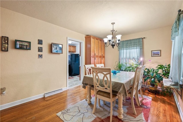 dining room with an inviting chandelier, hardwood / wood-style floors, and a textured ceiling