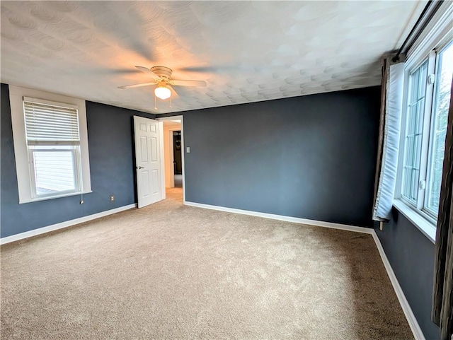 carpeted empty room with ceiling fan and a healthy amount of sunlight