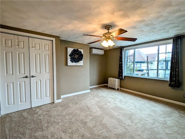 unfurnished bedroom featuring radiator, a wall mounted air conditioner, carpet flooring, ceiling fan, and a closet