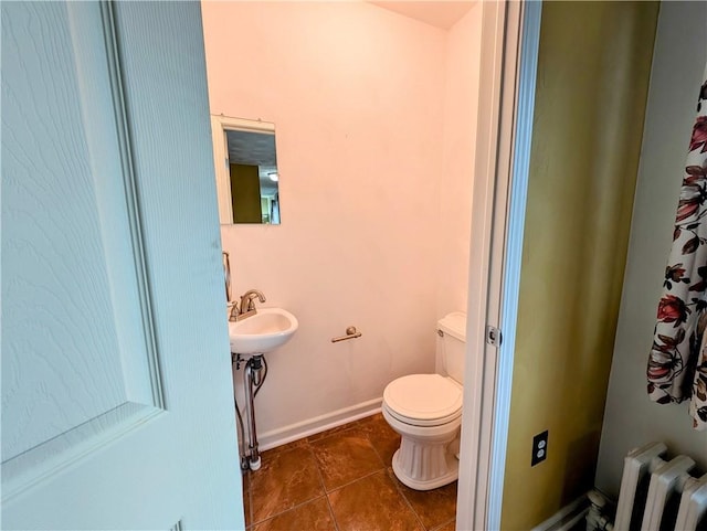 bathroom featuring tile patterned flooring, radiator heating unit, and toilet