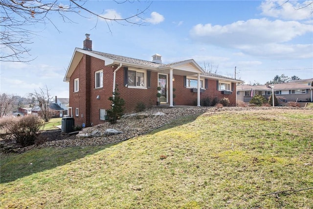 view of front of house with central AC unit and a front yard