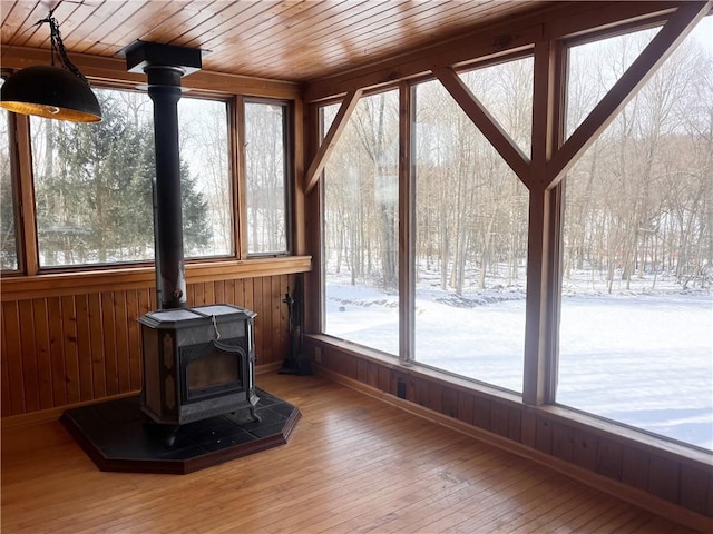 unfurnished sunroom featuring a wood stove and wooden ceiling