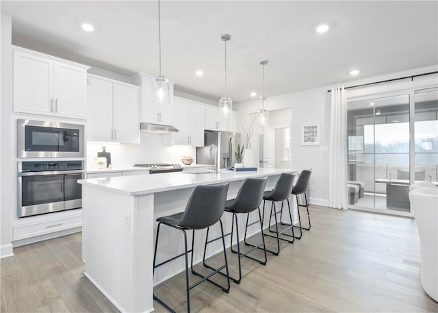 kitchen featuring pendant lighting, a center island with sink, white cabinets, and appliances with stainless steel finishes