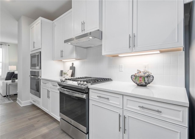 kitchen featuring stainless steel appliances, white cabinets, backsplash, and light hardwood / wood-style floors