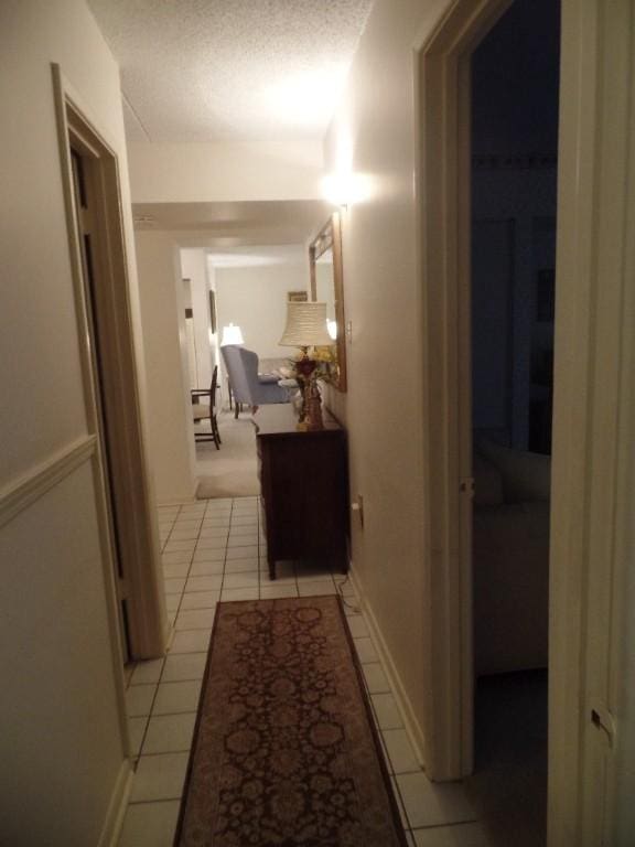 corridor with light tile patterned floors and a textured ceiling