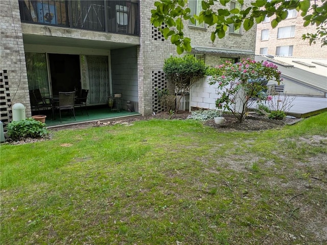 view of grassy yard with a balcony