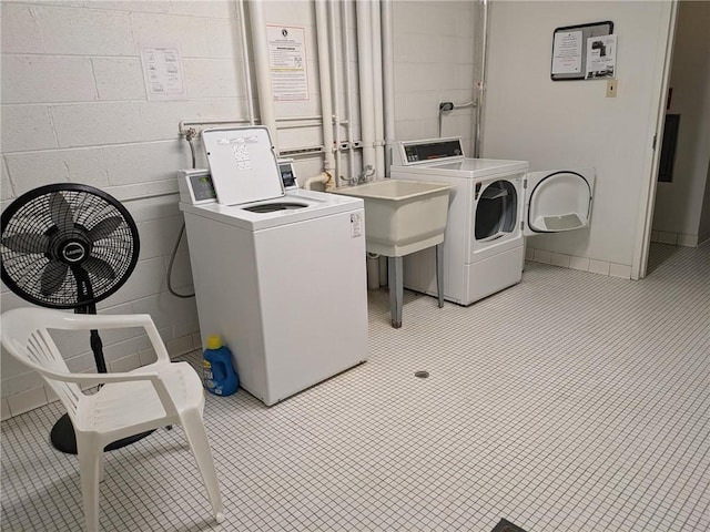 shared laundry room with washer and dryer and concrete block wall