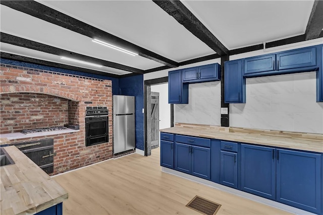 kitchen featuring blue cabinets, wooden counters, beamed ceiling, and appliances with stainless steel finishes