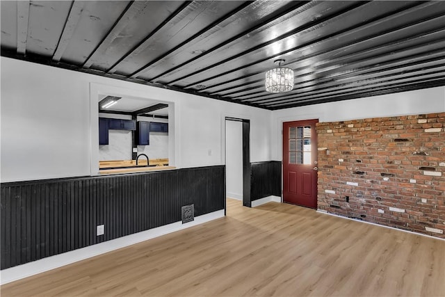 interior space with brick wall, sink, light hardwood / wood-style floors, and a notable chandelier