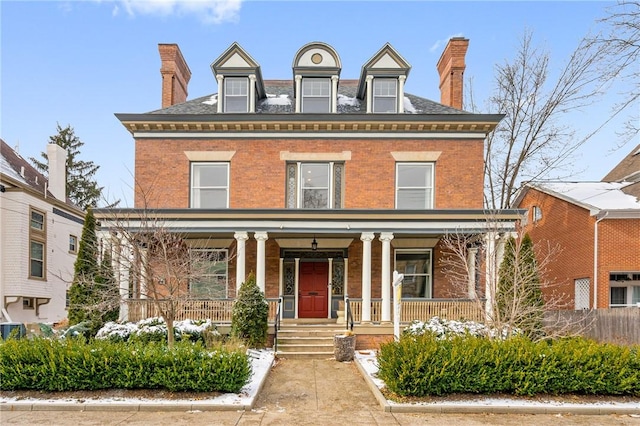 view of front of property with a chimney, a porch, and brick siding