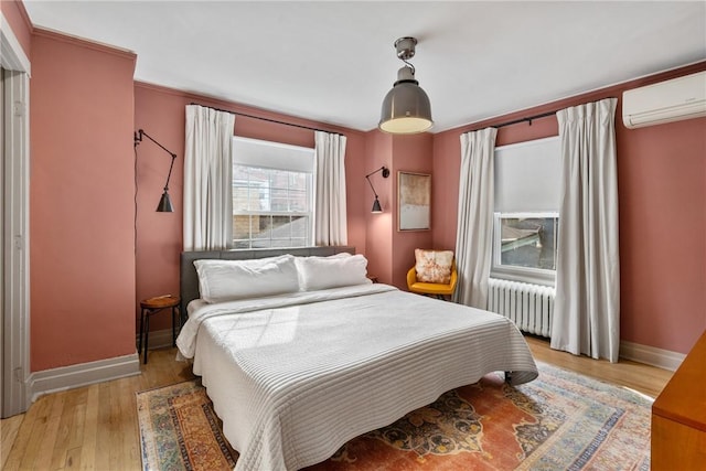 bedroom featuring a wall mounted air conditioner, radiator, and light hardwood / wood-style flooring