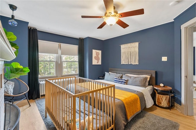 bedroom featuring radiator, ceiling fan, and light hardwood / wood-style flooring