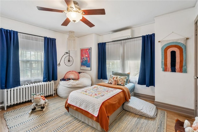 bedroom with hardwood / wood-style flooring, ceiling fan, radiator, and an AC wall unit