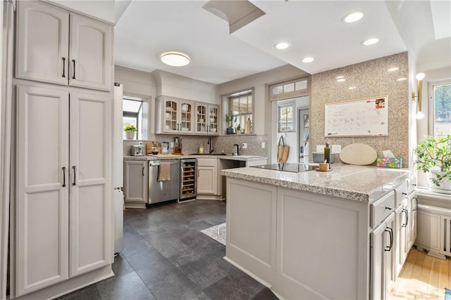 kitchen with hanging light fixtures, dishwasher, kitchen peninsula, black electric stovetop, and beverage cooler