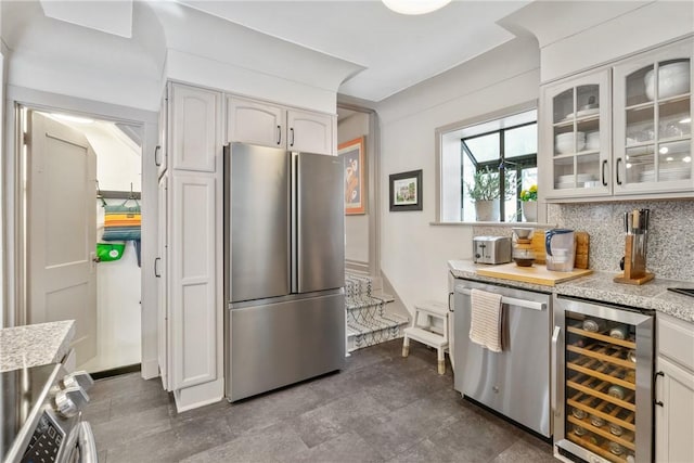 kitchen featuring white cabinetry, decorative backsplash, beverage cooler, and appliances with stainless steel finishes