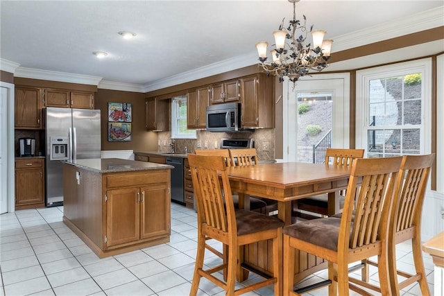 kitchen with crown molding, appliances with stainless steel finishes, hanging light fixtures, a center island, and decorative backsplash