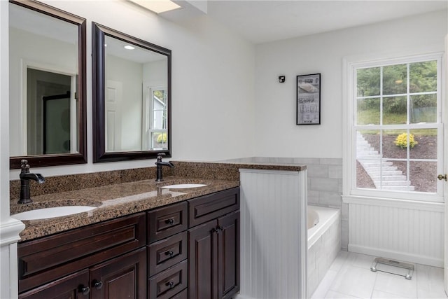 bathroom featuring vanity, tile patterned flooring, and tiled tub