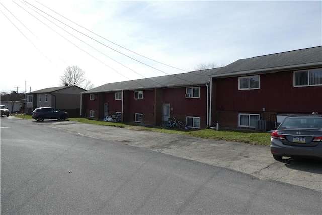 view of property exterior with brick siding, cooling unit, and a residential view