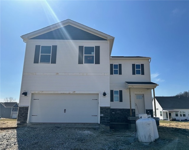 view of front of home with gravel driveway, a garage, and stone siding