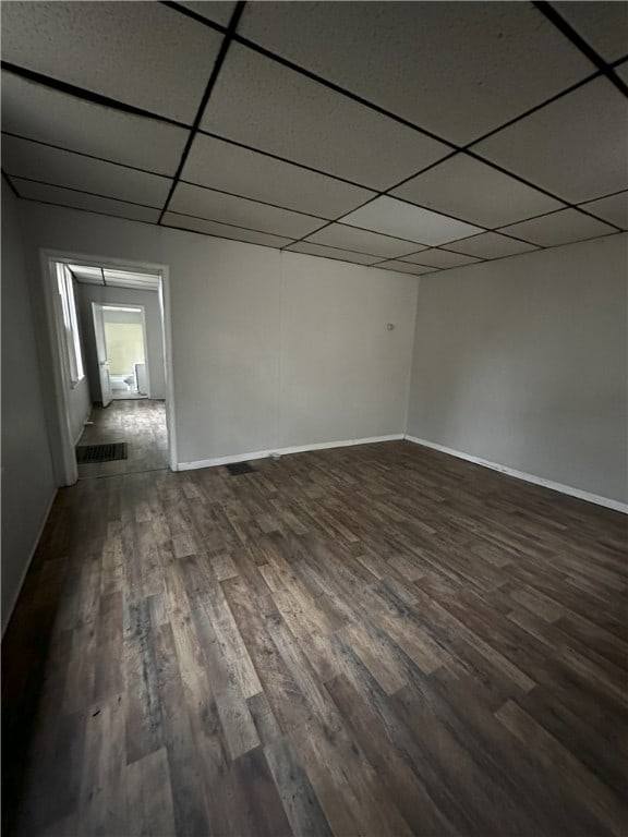 spare room featuring a paneled ceiling, baseboards, and dark wood-style flooring