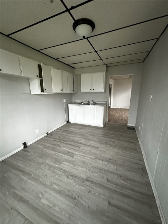 kitchen with white cabinetry, wood finished floors, and baseboards