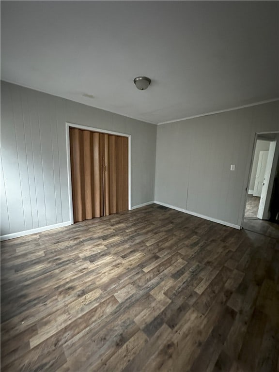unfurnished room featuring baseboards and dark wood finished floors