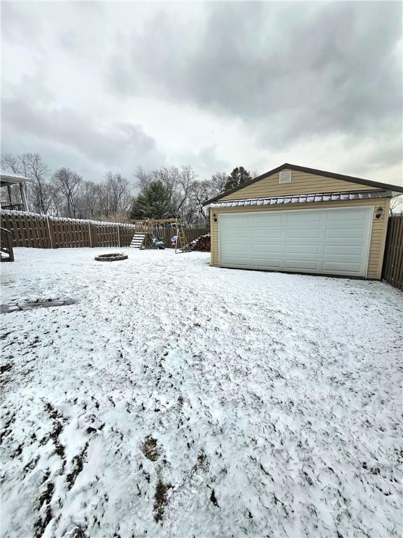 yard layered in snow featuring an outbuilding and a garage