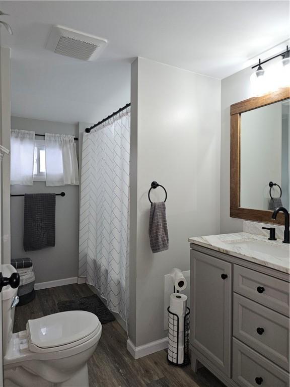 bathroom with vanity, hardwood / wood-style flooring, curtained shower, and toilet