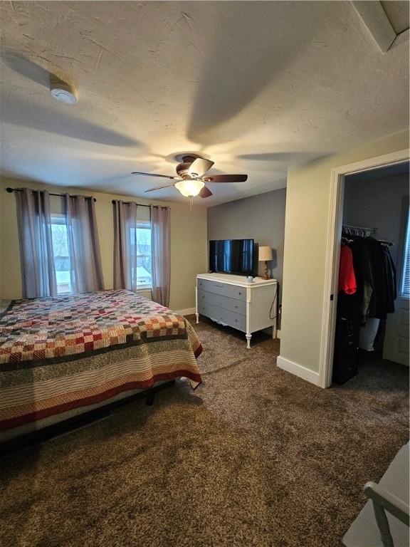 bedroom featuring ceiling fan, carpet, a textured ceiling, a walk in closet, and a closet