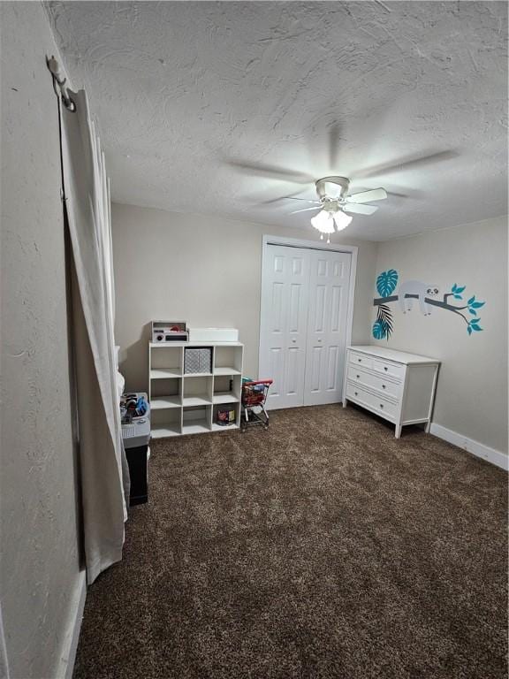 interior space featuring dark colored carpet, ceiling fan, and a textured ceiling