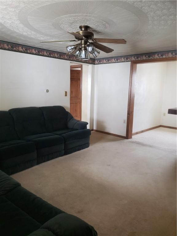 carpeted living room featuring ceiling fan and a textured ceiling