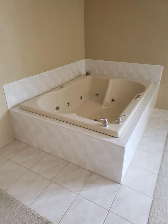 bathroom with tiled bath and tile patterned flooring