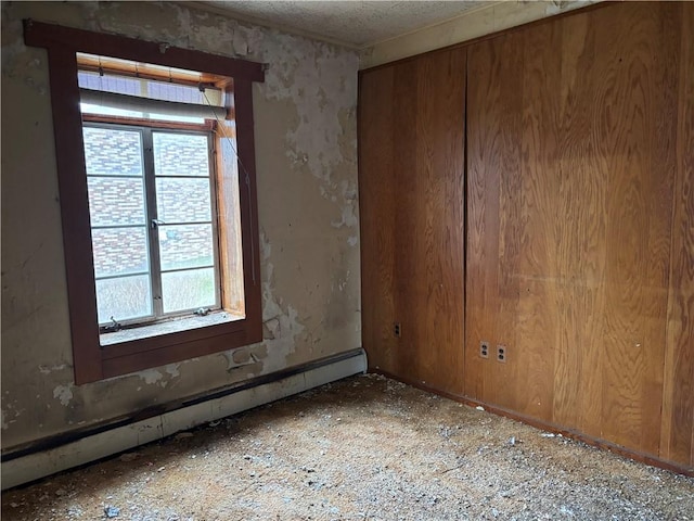 unfurnished room featuring a baseboard radiator, plenty of natural light, and a textured ceiling