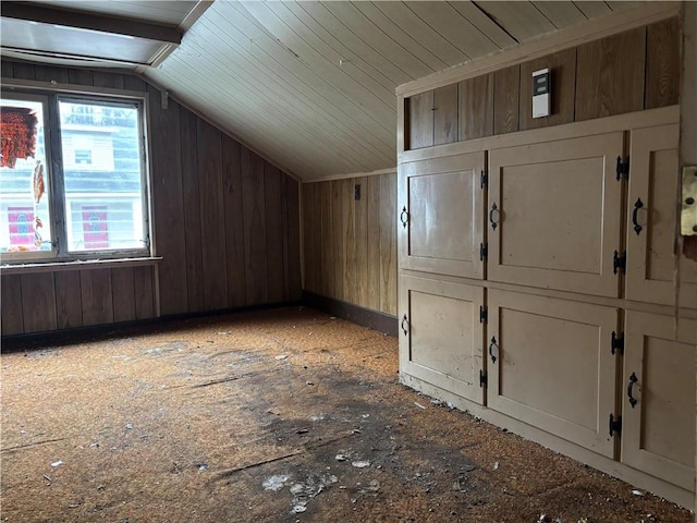 bonus room featuring vaulted ceiling and wood walls