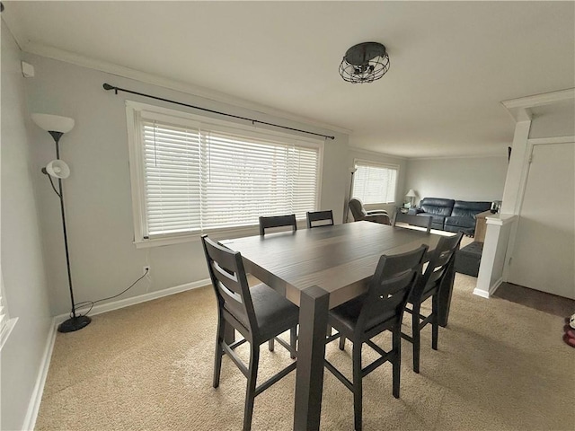 dining area with crown molding and light carpet