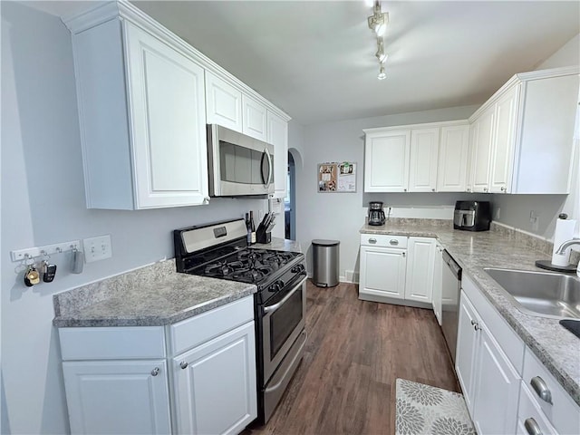 kitchen featuring sink, rail lighting, stainless steel appliances, dark hardwood / wood-style floors, and white cabinets