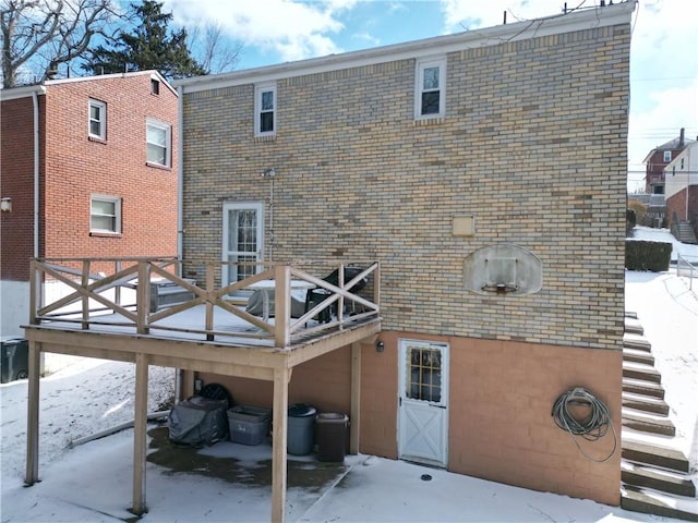 snow covered rear of property featuring a wooden deck