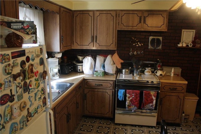 kitchen with white refrigerator, light tile patterned floors, sink, and range with electric cooktop