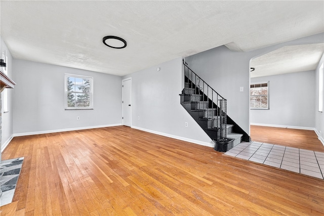 unfurnished living room featuring a healthy amount of sunlight, hardwood / wood-style floors, and a textured ceiling