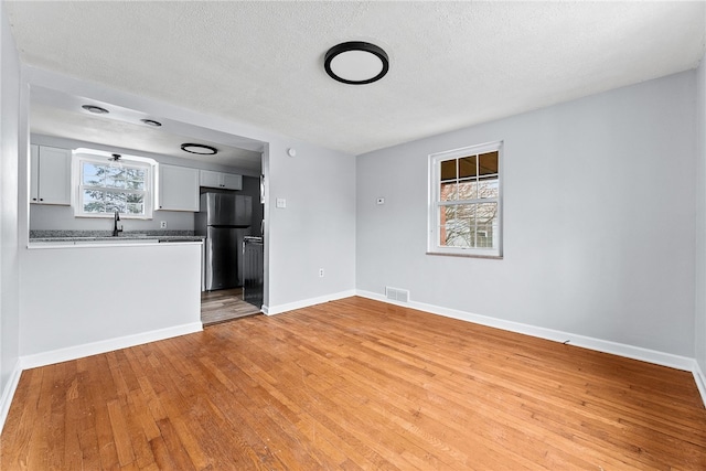 unfurnished living room with light hardwood / wood-style flooring and a textured ceiling