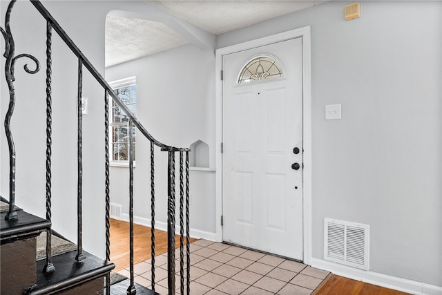 foyer entrance featuring a textured ceiling and light hardwood / wood-style flooring