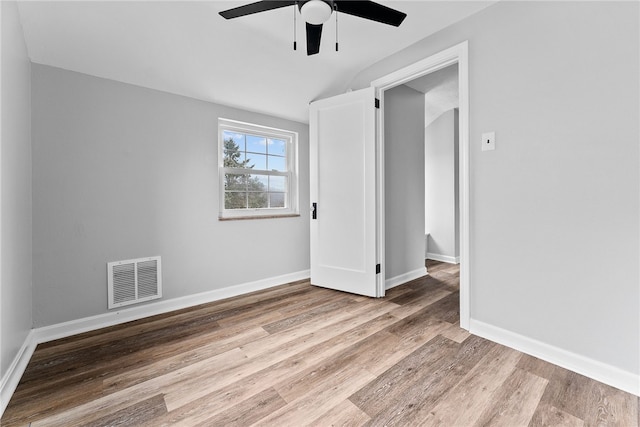 empty room with ceiling fan, vaulted ceiling, and light hardwood / wood-style flooring