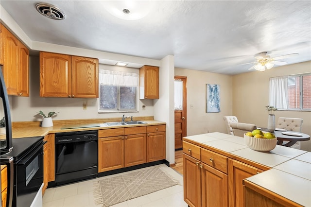 kitchen with sink, tile countertops, ceiling fan, and black appliances