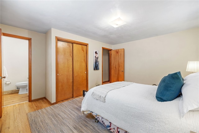 bedroom featuring a closet, ensuite bathroom, and light hardwood / wood-style flooring