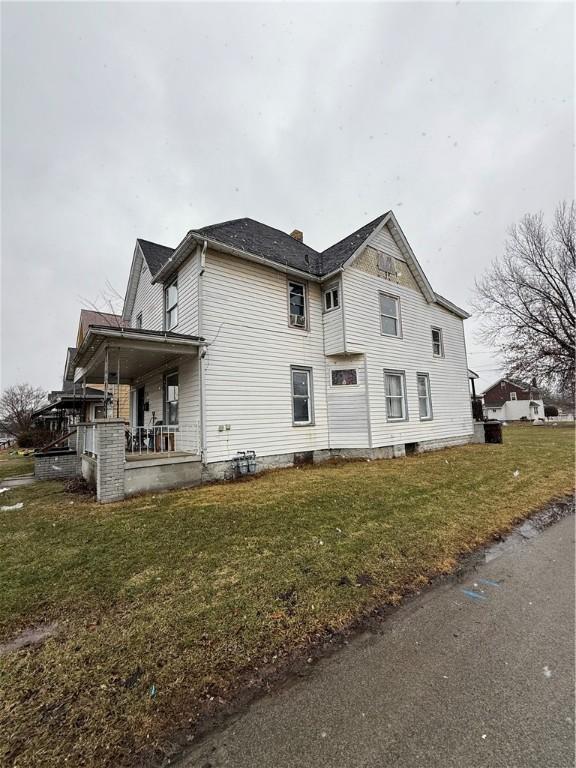 view of side of property featuring covered porch and a lawn