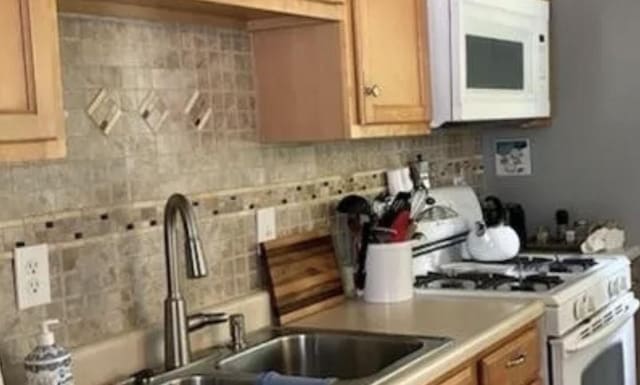 kitchen with white appliances, sink, and backsplash