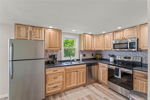 kitchen with sink, backsplash, appliances with stainless steel finishes, and light hardwood / wood-style flooring